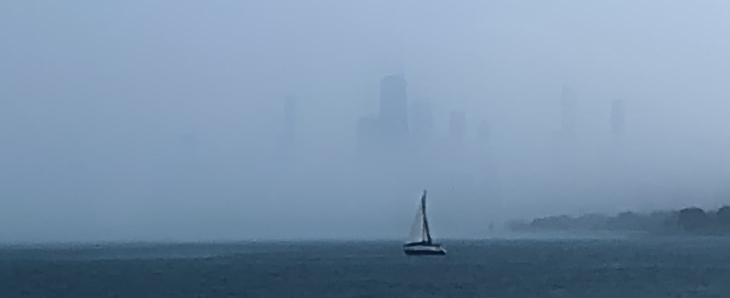 a sailboat sailing towards misty towers on an overcast day